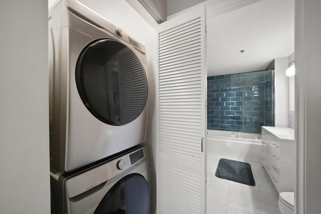 clothes washing area featuring laundry area, stacked washer / dryer, and tile patterned flooring