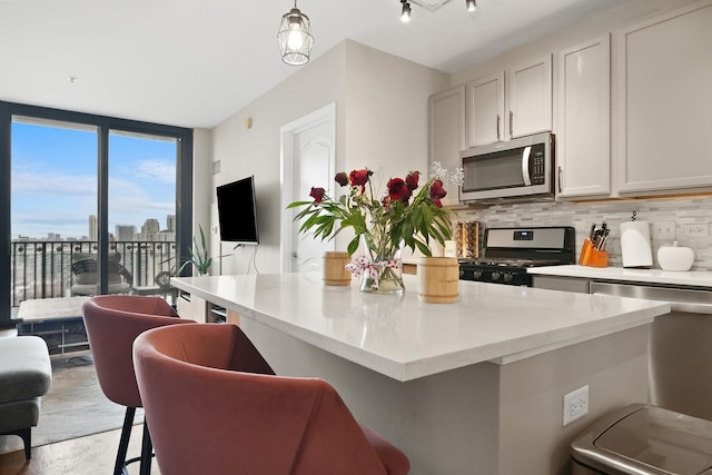 kitchen featuring a kitchen breakfast bar, appliances with stainless steel finishes, a center island, tasteful backsplash, and decorative light fixtures