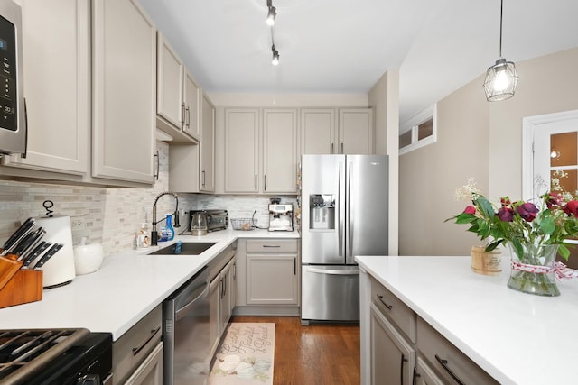 kitchen featuring appliances with stainless steel finishes, light countertops, a sink, and backsplash