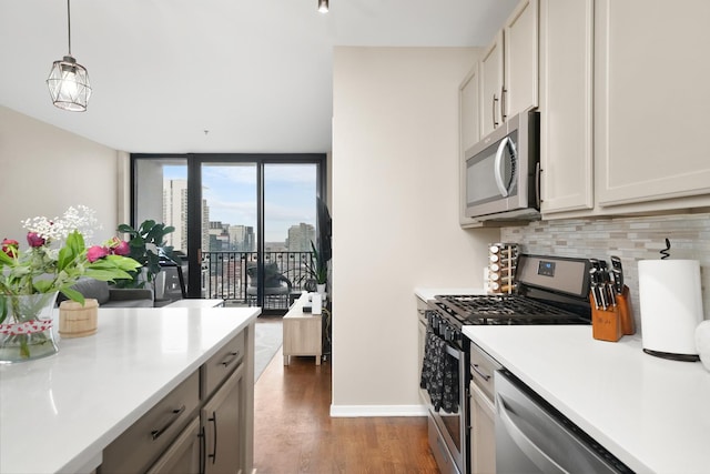 kitchen with light countertops, appliances with stainless steel finishes, hanging light fixtures, dark wood-style floors, and tasteful backsplash