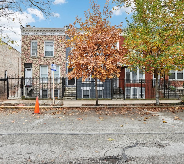 multi unit property with a fenced front yard and stone siding