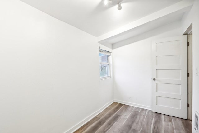 spare room with wood finished floors, visible vents, and baseboards