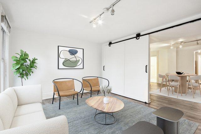 living room with a barn door, wood finished floors, and rail lighting