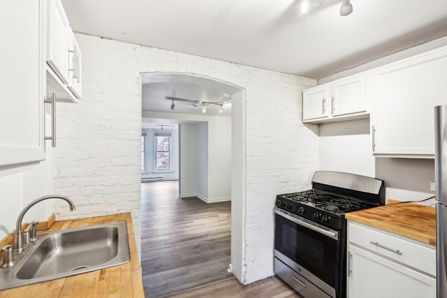 kitchen featuring wood finished floors, a sink, white cabinets, wooden counters, and gas range