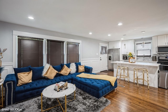 living area featuring dark wood-style floors, recessed lighting, a decorative wall, and wainscoting