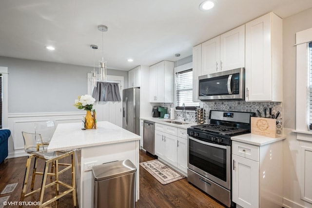 kitchen featuring a kitchen island, a sink, appliances with stainless steel finishes, dark wood-style floors, and tasteful backsplash