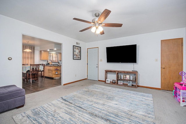 living area with carpet flooring, ceiling fan, and baseboards