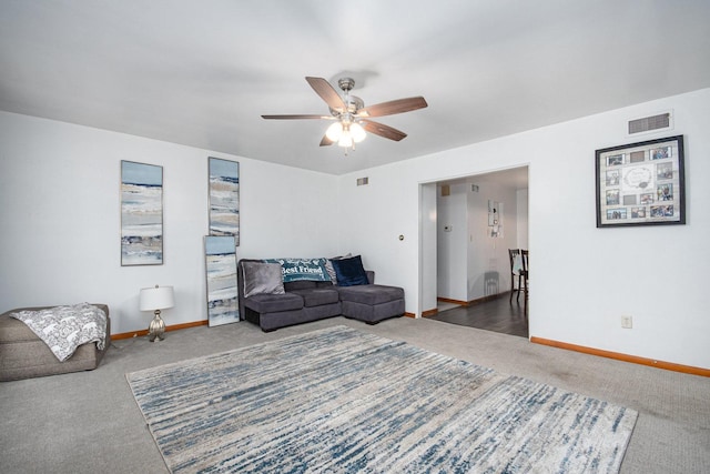 living area featuring ceiling fan, carpet floors, visible vents, and baseboards