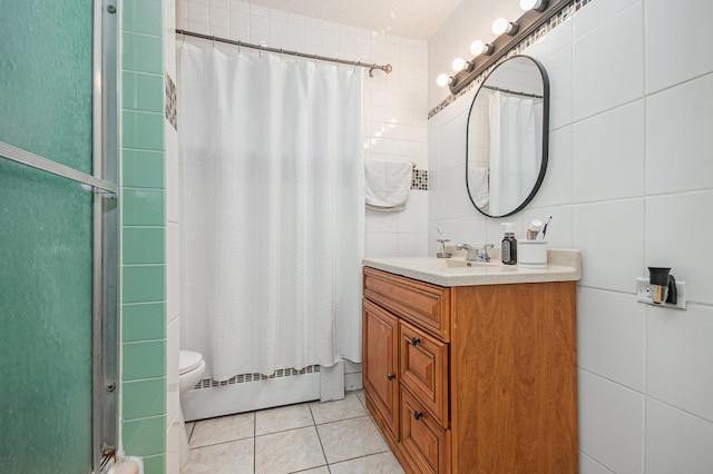 full bathroom with toilet, tile patterned floors, vanity, a baseboard heating unit, and tile walls