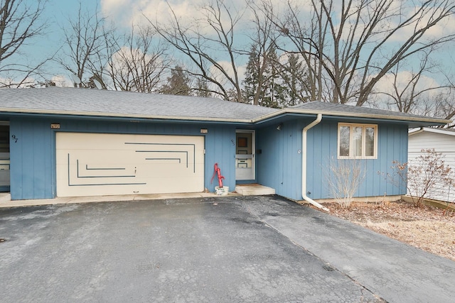 ranch-style house with an attached garage, driveway, and roof with shingles