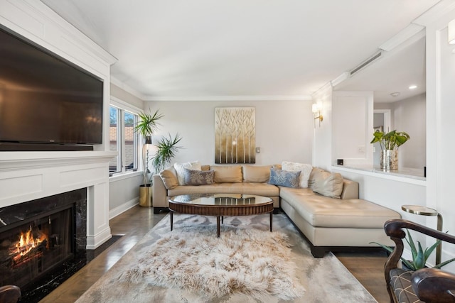 living room featuring baseboards, wood finished floors, a fireplace with flush hearth, and crown molding