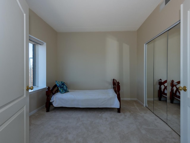 bedroom with a closet, carpet flooring, visible vents, and baseboards