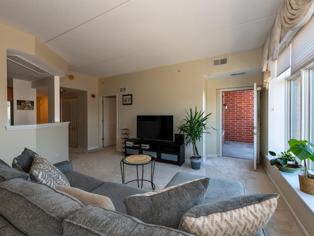 living room with baseboards, visible vents, and light colored carpet