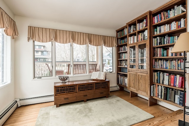 living area with a baseboard heating unit and wood finished floors