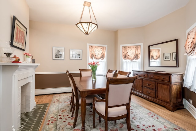 dining area with baseboards, a fireplace, light wood-style flooring, and baseboard heating