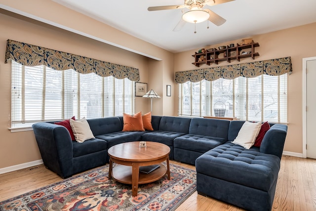 living area featuring a healthy amount of sunlight, ceiling fan, baseboards, and wood finished floors