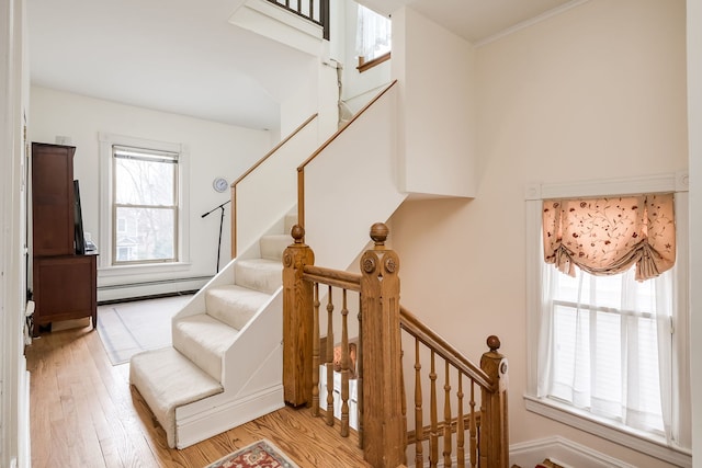 stairs featuring a baseboard heating unit and wood finished floors