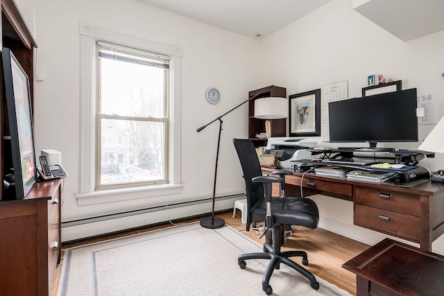 home office featuring a baseboard heating unit and wood finished floors