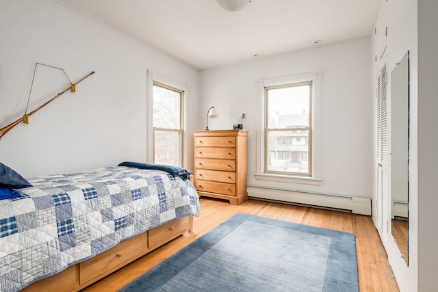 bedroom with light wood finished floors and baseboard heating