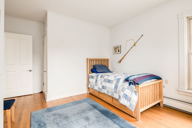 bedroom with ornamental molding, baseboard heating, baseboards, and hardwood / wood-style floors