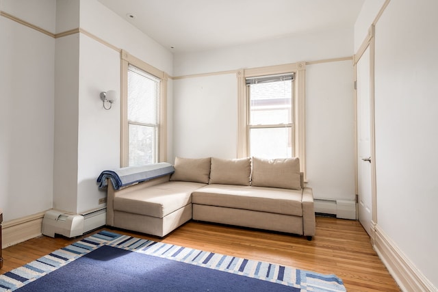 living room featuring a healthy amount of sunlight, light wood-style floors, and a baseboard heating unit