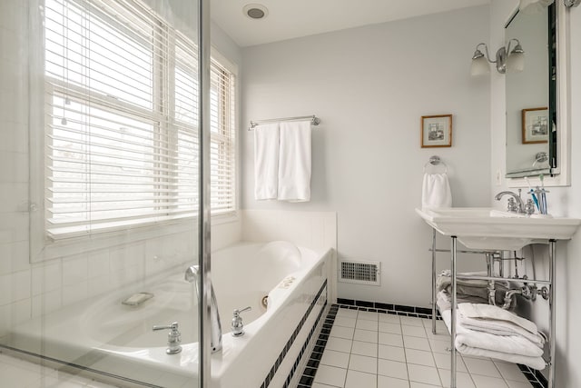 full bath featuring tile patterned flooring, visible vents, baseboards, and a bath