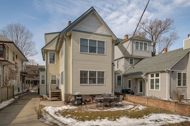 snow covered rear of property with entry steps and a patio area