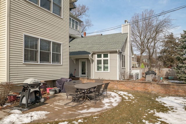 back of property featuring a shingled roof, a chimney, a patio area, and fence