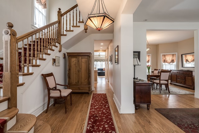 foyer entrance with stairs, wood finished floors, a wealth of natural light, and baseboards