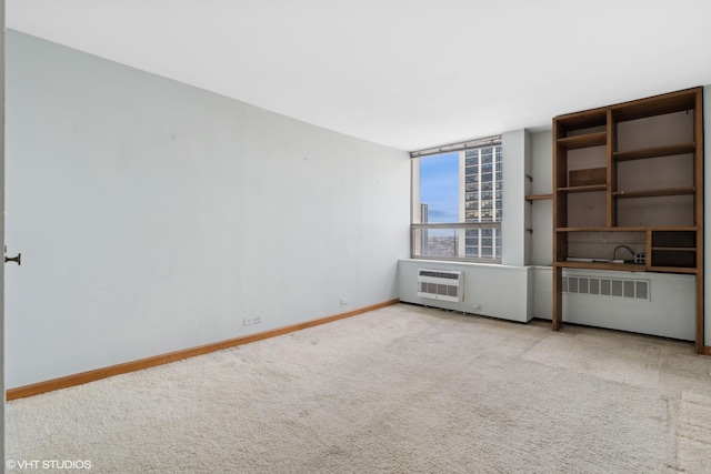 carpeted empty room with radiator, a wall mounted air conditioner, and baseboards