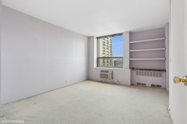 carpeted spare room with a wall unit AC and radiator heating unit