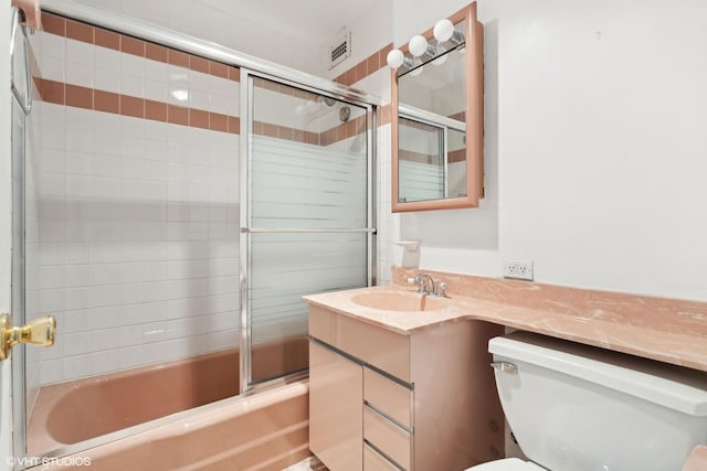 bathroom featuring visible vents, enclosed tub / shower combo, vanity, and toilet