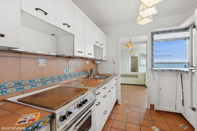 kitchen with light tile patterned floors, electric range, radiator heating unit, white cabinets, and a sink