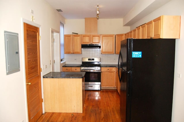 kitchen featuring electric panel, stainless steel range with gas cooktop, under cabinet range hood, backsplash, and freestanding refrigerator