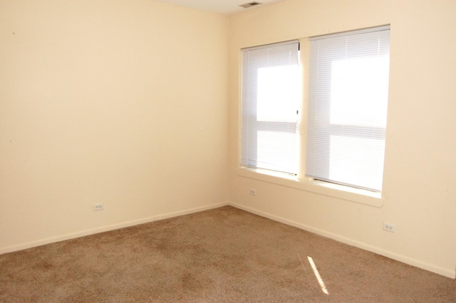 carpeted empty room featuring baseboards and visible vents