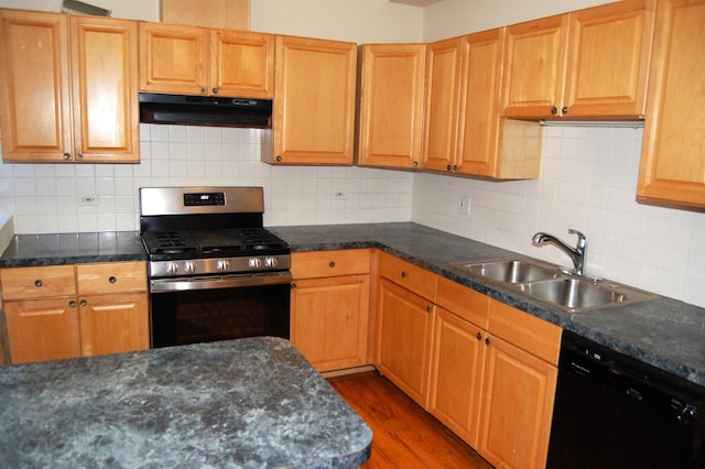 kitchen featuring wood finished floors, black dishwasher, under cabinet range hood, stainless steel gas range oven, and a sink