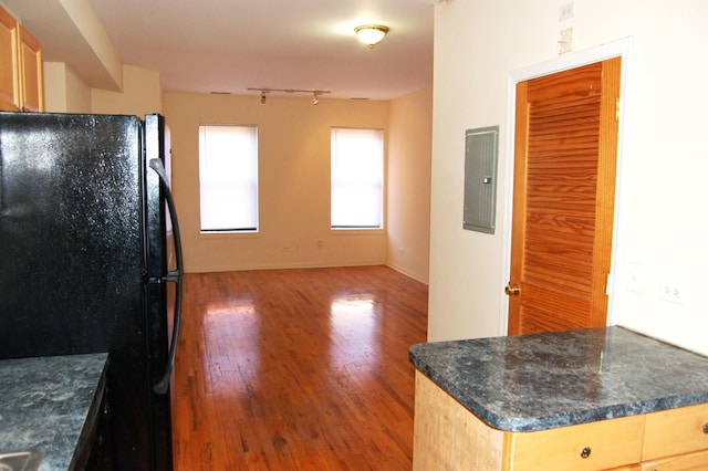 kitchen featuring wood finished floors, dark countertops, electric panel, and freestanding refrigerator