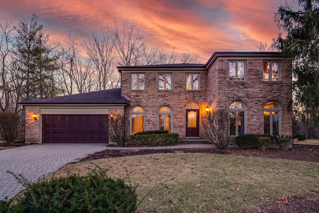 view of front of property with a garage, a front yard, decorative driveway, and brick siding