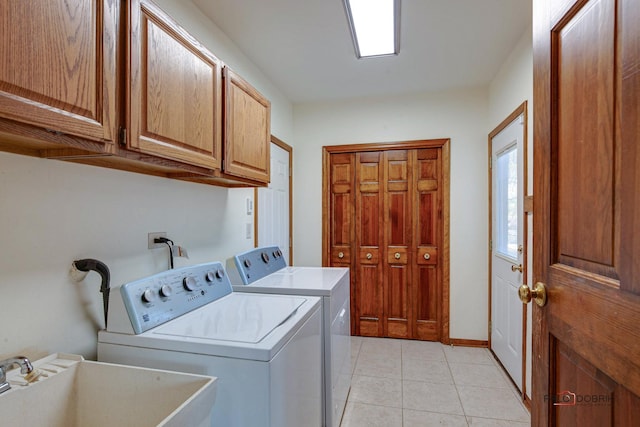 laundry area featuring light tile patterned floors, a sink, baseboards, independent washer and dryer, and cabinet space