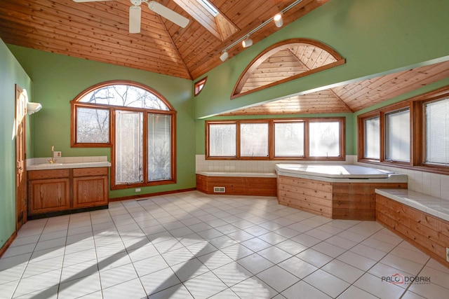 bathroom with a skylight, wood ceiling, a garden tub, and tile patterned floors