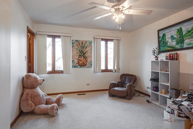 sitting room with carpet floors, a ceiling fan, visible vents, and baseboards