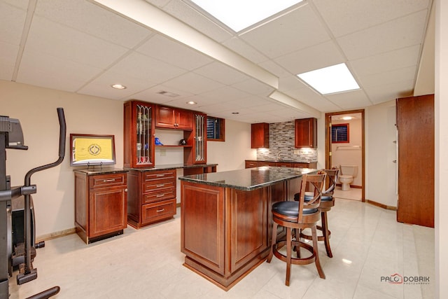 kitchen with tasteful backsplash, a breakfast bar area, a kitchen island, and dark brown cabinets