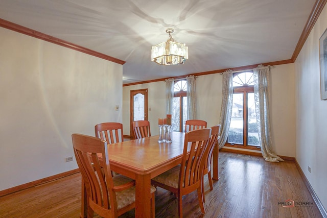 dining room with baseboards, ornamental molding, wood finished floors, and a notable chandelier