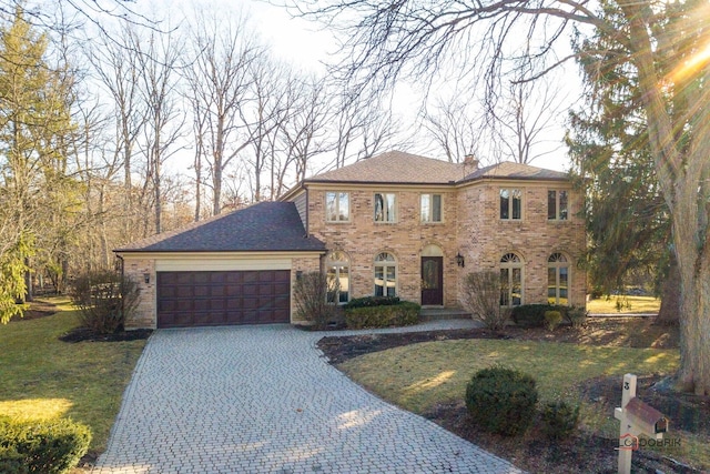 view of front of house featuring an attached garage, a front yard, decorative driveway, and brick siding