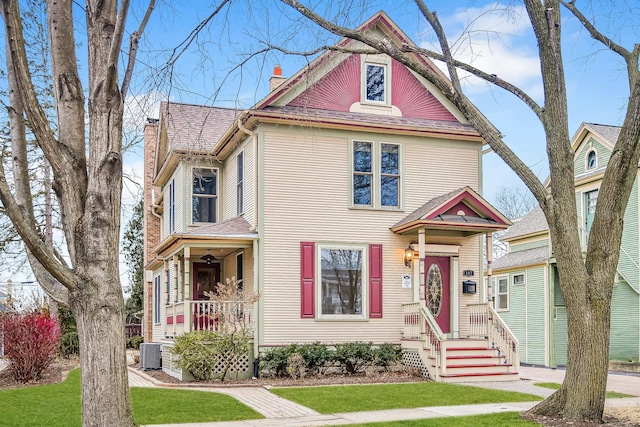 victorian house featuring central air condition unit, a chimney, and roof with shingles