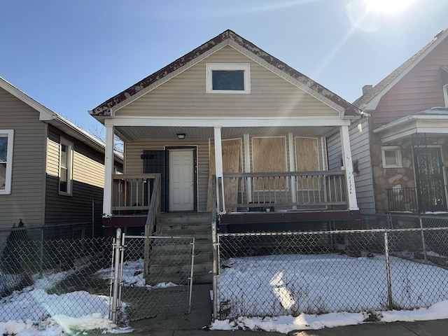 shotgun-style home with a porch, a fenced front yard, and a gate