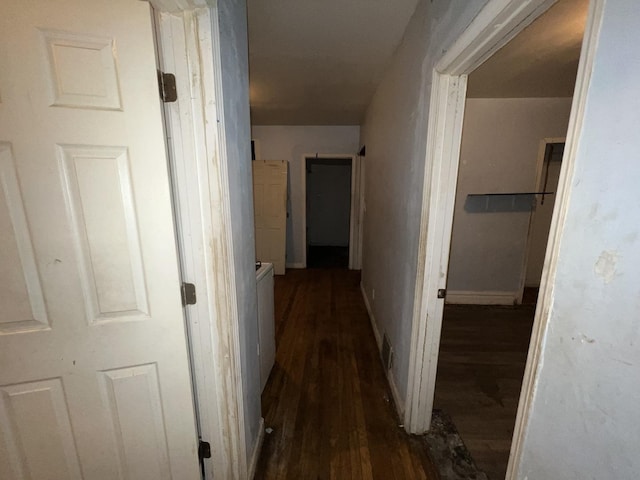 hallway featuring baseboards and dark wood-type flooring