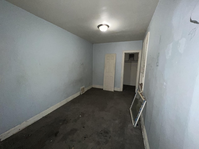 unfurnished bedroom featuring concrete flooring, a closet, visible vents, and baseboards