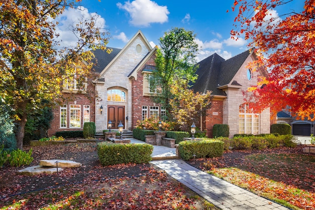 french country home featuring brick siding and roof with shingles