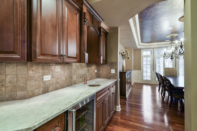 kitchen featuring light stone counters, beverage cooler, a sink, dark wood-style floors, and tasteful backsplash